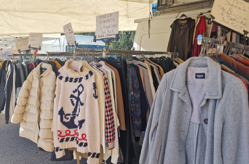 Il maglione con l'ancora e i cappotti appesi, sotto i cartelli scritti a mano