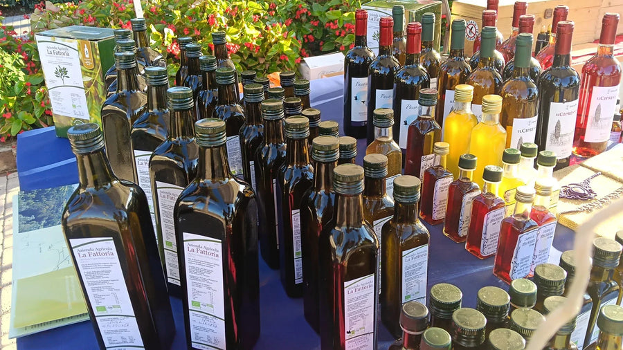 Il banco della Fattoria di Afelba alla fiera: le bottiglie dell'olio extravergine biologico in fila sul tavolo, con la confezione da 5 litri e altre bottiglie dietro