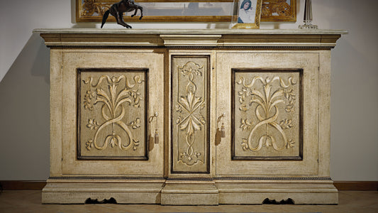 La credenza 607 vista di fronte: le tre campiture con i mazzi di foglie a rilievo e la fascia dentellata sotto il piano