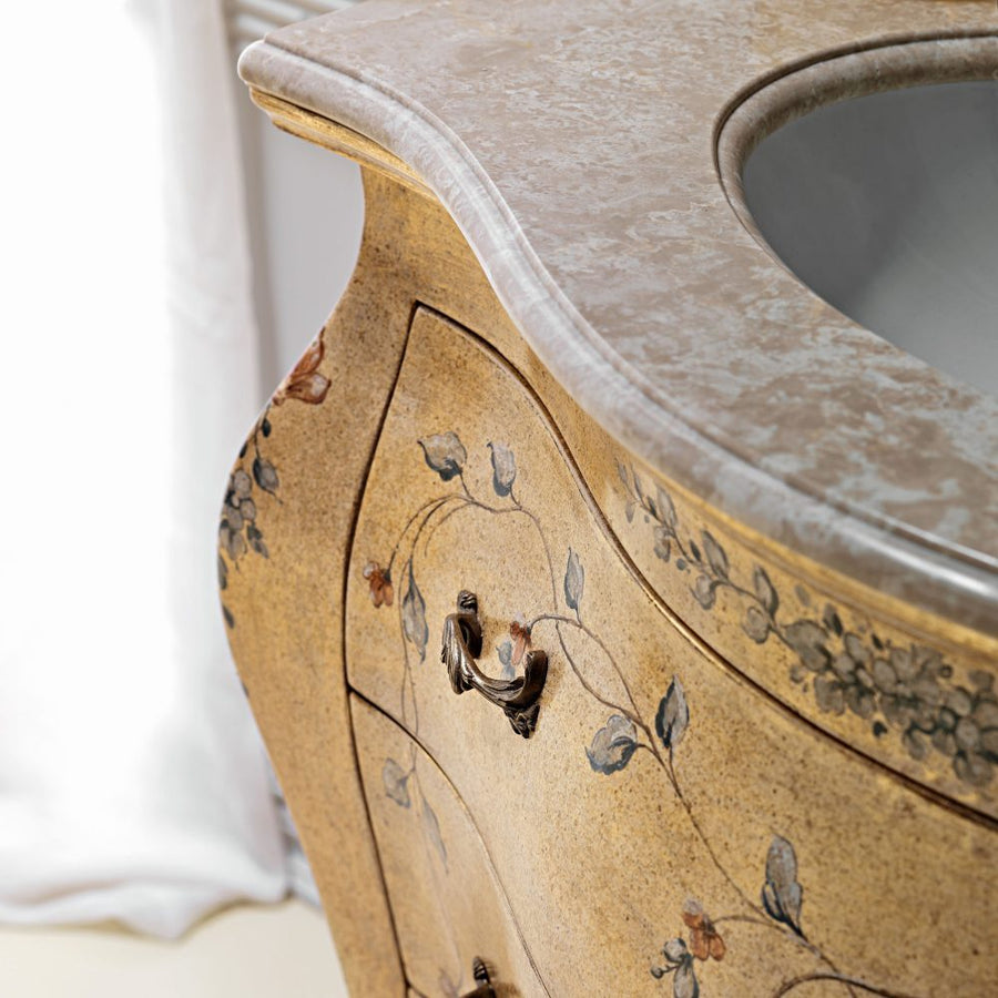 The side close-up: the curve of the drawer, the painted vine scroll and the edge of the marble top