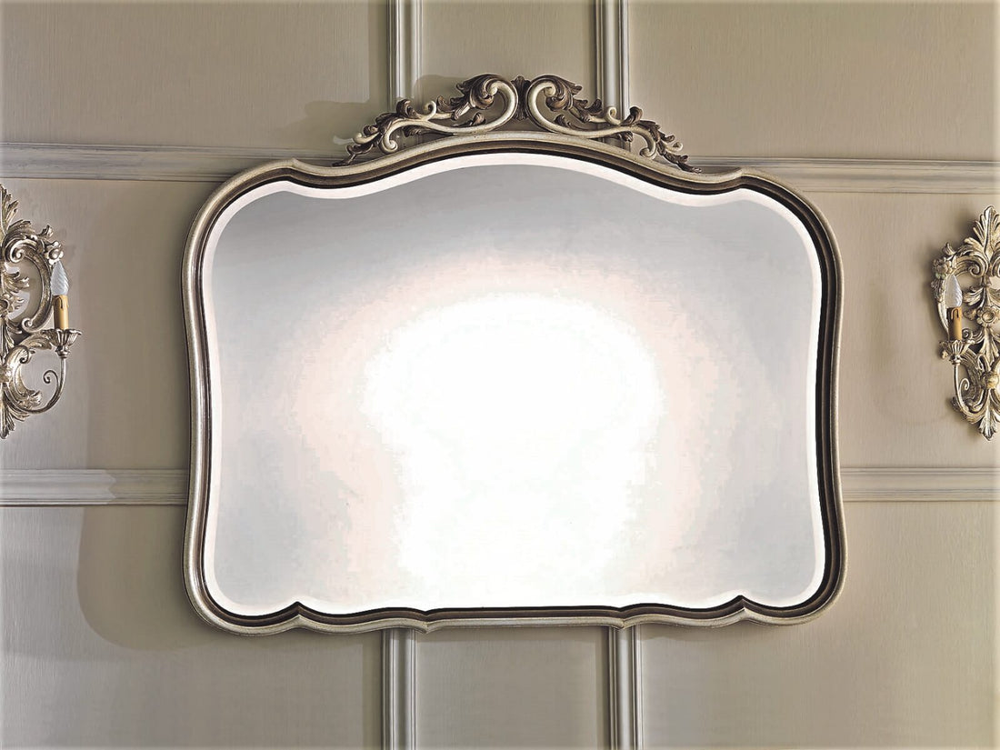 The 1580 mirror between two wall lights: the shaped profile and the carved crest at the centre top