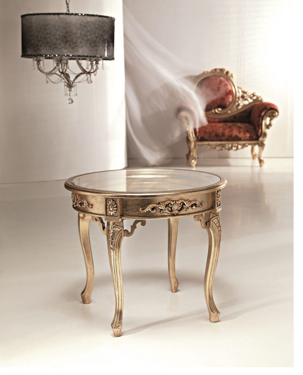 The round 2121 side table: the sabre legs and the shaped apron with the carving at the centre