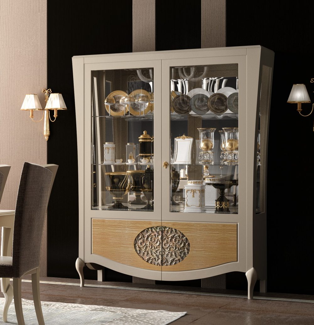 La vetrina 862 illuminata: le due ante a vetro, la fascia bassa in rovere naturale e l'ovale intagliato in argento