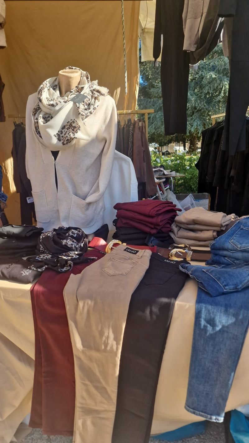 Il tavolo dei pantaloni piegati, con foulard e cinture, davanti a un manichino con la sciarpa