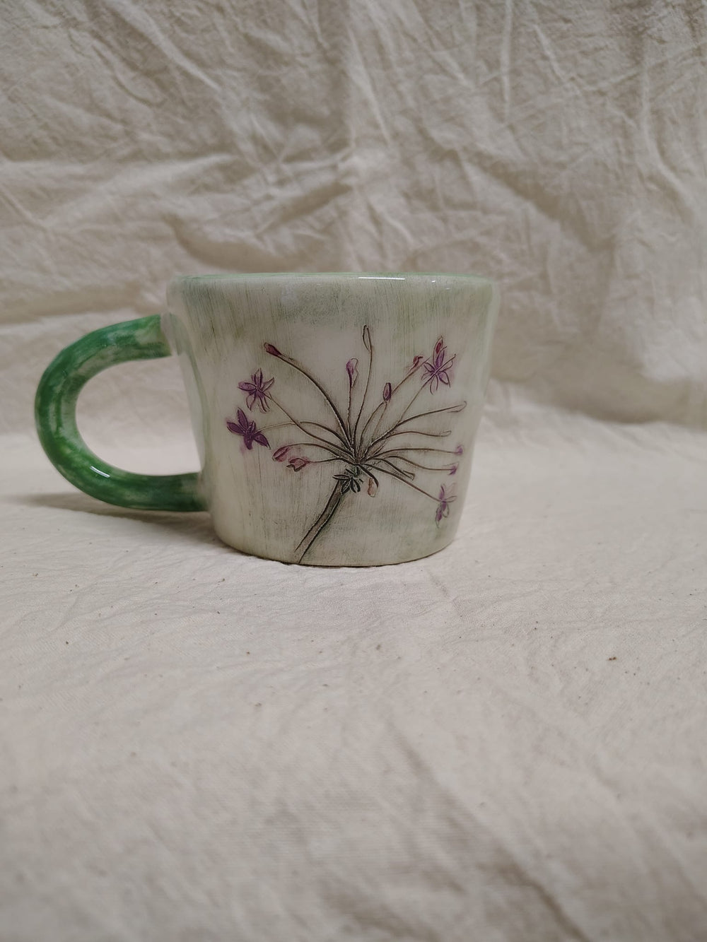 Tazza con un'ombrella di fiori viola e il manico verde