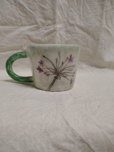 Tazza con un'ombrella di fiori viola e il manico verde