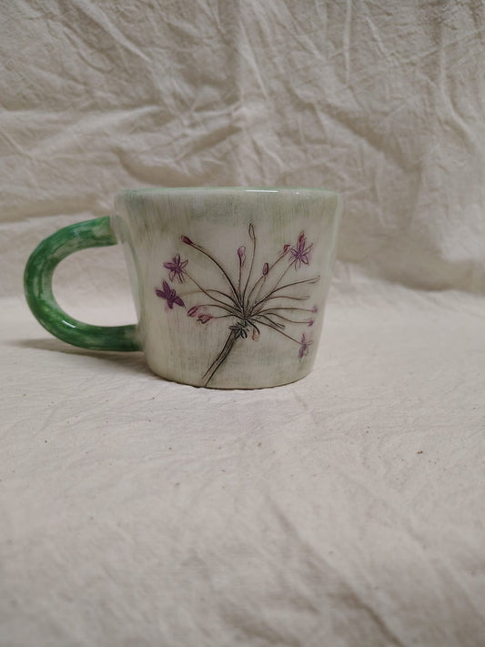 Tazza con un'ombrella di fiori viola e il manico verde