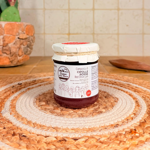 Il vasetto da 210 g di Composta di cipolle rosse, scuro e violaceo, sul centrino all'uncinetto