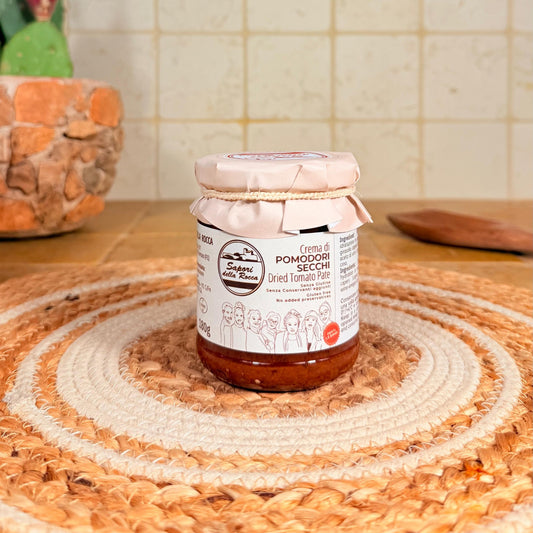 Il vasetto di Crema di pomodori secchi con l'etichetta rossa, sul centrino all'uncinetto