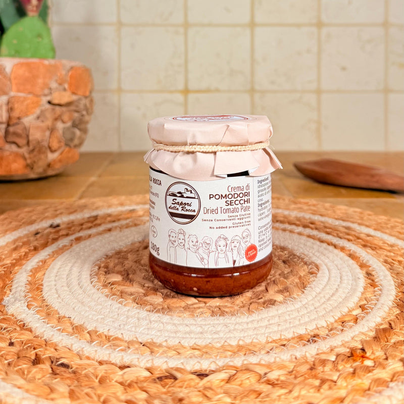Il vasetto di Crema di pomodori secchi con l'etichetta rossa, sul centrino all'uncinetto