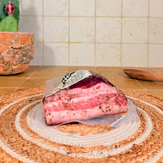Il trancio triangolare di guanciale sottovuoto, con la crosta di pepe sul bordo
