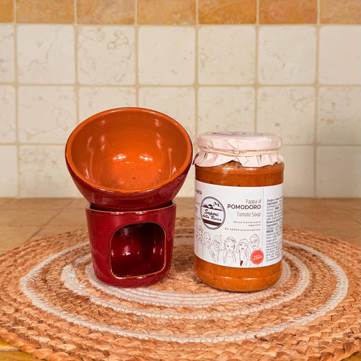 Il fornellino rosso di terracotta con la ciotola sopra, accanto al vasetto di pappa al pomodoro