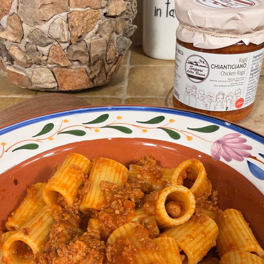 Un piatto di rigatoni conditi col ragù di pollo, il vasetto aperto sullo sfondo