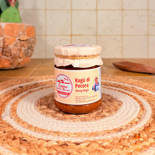 Il vasetto di Ragù di pecora con l'etichetta rosa, sul centrino all'uncinetto
