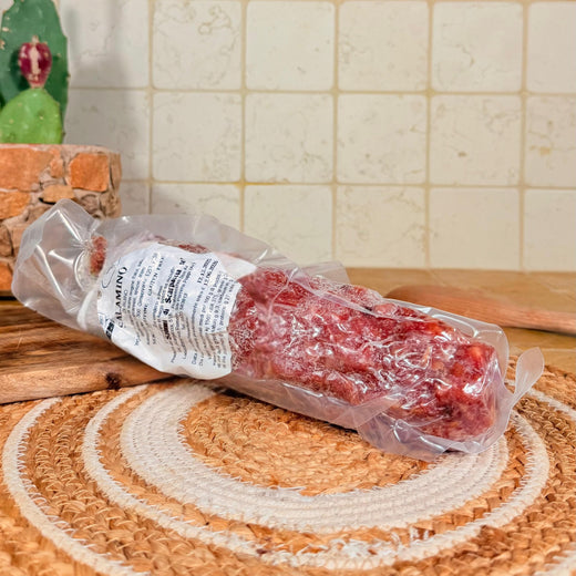 Il salame intero sottovuoto, appoggiato sul centrino all'uncinetto