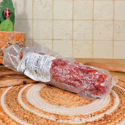 Il salame intero sottovuoto, appoggiato sul centrino all'uncinetto