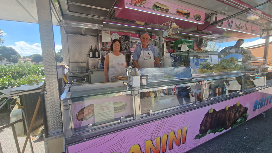 Il banco di Aiello Teresa alle Cascine: il furgone dei panini aperto sul piazzale, con due persone dietro il bancone e la vetrina refrigerata in primo piano