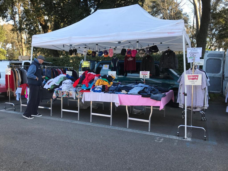 Il banco visto di lato, con il tavolo centrale dei capi piegati e i cartelli «giubbotti jeans firmati» e «Levi's camicie»